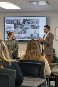 Kevin Welch speaking to Journey Payroll & HR team members during a company meeting with remote participants on screen.