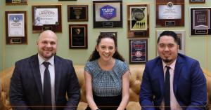 Katelyn Morgan seated with two colleagues in The Valley Law Group office with awards displayed on the wall.