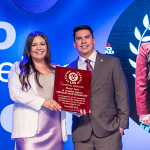 Hector Cano at his National Director promotion event in Miami, standing on stage in formal attire.