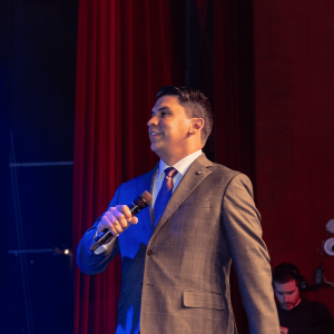 Hector Cano speaking on stage at a leadership event in Miami.