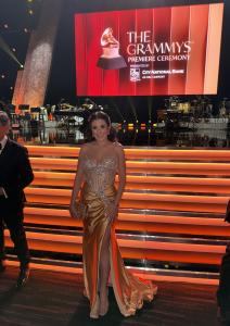 Farrah Mechael attending the Grammy Awards Premiere Ceremony in front of the stage and Grammy logo.