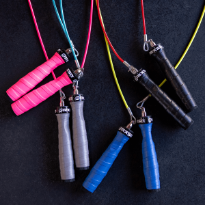 Multiple Rx Jump Rope 2.0 jump ropes displayed on a dark background, featuring black, blue, gray, and pink ergonomic handles with matching and contrasting colored cables, highlighting customizable handle wraps and cable options