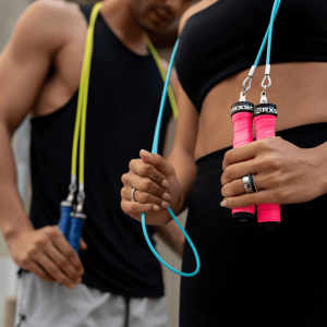 Close-up of two athletes holding the Rx Jump Rope 2.0 Customizable with bright pink handle covers and colored cables, highlighting the customizable handle and cable options.