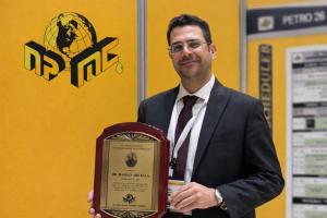 Dr. Hassan Abdalla holding the 2025 Harold Ensign Engineering Excellence Award presented by the National Petroleum Management Corporation