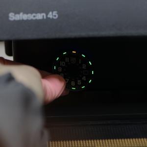 Luminox watch dial glowing in the dark with green and orange Luminox Light Technology (LLT) tubes, demonstrating constant night visibility during illumination test.