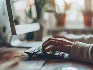 A woman typing on a computer using a trustworthy AI system.
