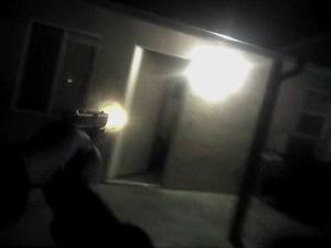 After dodging the tossed yearbook, Modesto Police officer Dave Wallace, in this screen grab, fires his service weapon at Jesse Montelongo, who is retreating into his house.