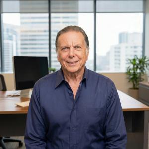 man in blue shirt smiling sitting at corporate desk