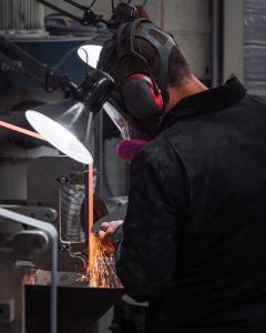 STEELPORT co-founder and bladesmith making an 8" Chef Knife at the grinding machine with sparks flying