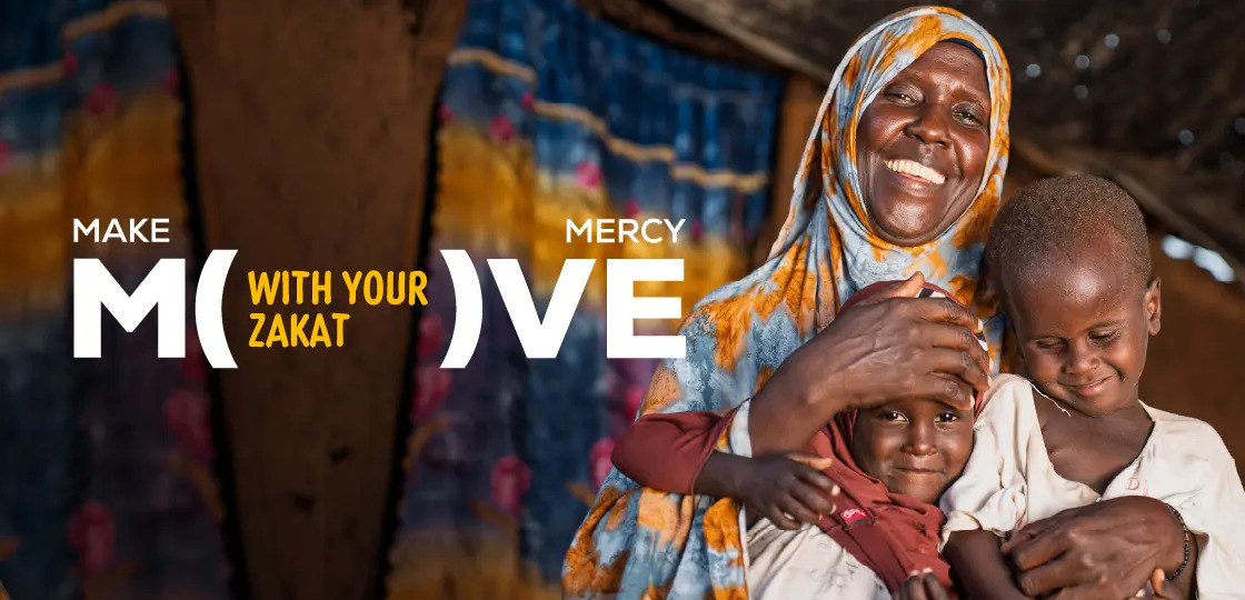 Smiling mother holding her children during Ramadan food aid distribution supported by Zakat donations from Al Mustafa Welfare Trust.