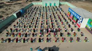 Aerial view of families seated in rows receiving Ramadan food packs distributed by Al Mustafa Welfare Trust.