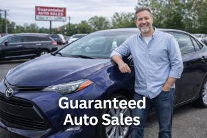 Smiling customer standing beside a blue used sedan at Guaranteed Auto Sales car lot in Johnston, Rhode Island.