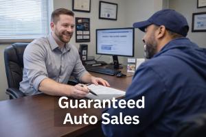 Sales representative reviewing in-house auto financing paperwork with a customer at Guaranteed Auto Sales in Johnston, Rhode Island.