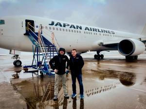 Steve Giordano and Bob Allen standing in front of a Boeing 767 in Japan Airlines Paint on an overcast day in Arkansas