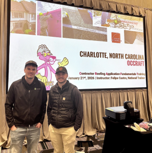 Two men in Hatch Homes and Carhartt gear smiling in front of a projector screen displaying the Owens Corning OCC Craft event details for January 21, 2026 in Charlotte, NC, featuring the Pink Panther mascot and training title "Contractor Roofing Applicatio