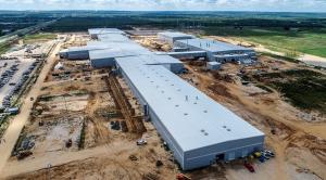 Aerial drone view of a large industrial manufacturing complex under construction in Texas, featuring multiple connected steel buildings and surrounding construction equipment across a wide site.