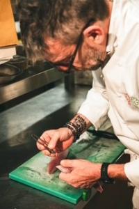 Double MICHELIN-Starred Chef Giorgio Servetto in action in the kitchen, plating a refined dish with focused precision, showcasing his disciplined technique and creative, ingredient-led approach.