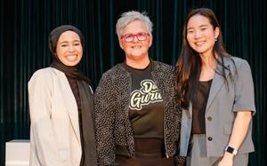 Three women stand on a stage at The Forum event.