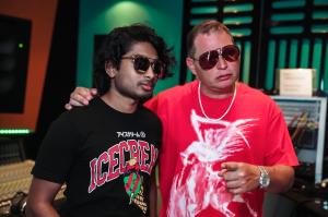 Ashwin Gane stands beside producer Scott Storch in a recording studio, with Scott’s arm around his shoulder and equipment visible in the background.
