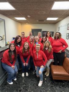13 Team Members are posed in matching red jackets