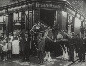 Historic photograph of The Lord Nelson pub on Trafalgar Street in Leith with local residents and a horse delivery cart outside the building in the early 1900s.
