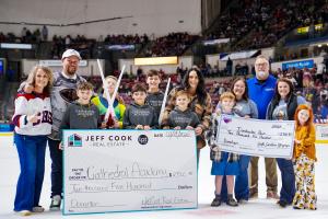 Representatives from Jeff Cook Real Estate LPT Realty present donation checks on the ice to Dorchester Paws and Cathedral Academy during a South Carolina Stingrays game.