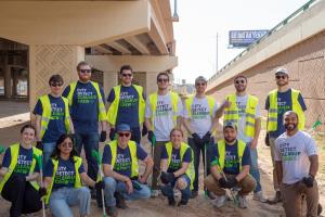 A group of people wearing T-Shirts that say "City Detect Cleanup Crew" and neon yellow vests pose for a picture.