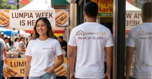 Two people modeling white Lumpia Week SA T-shirts at an outdoor market; the front shows the Lumpia Week SA logo and the back shows the logo with “March 10–16, 2026.”