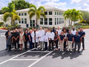 A group of clinician, nurses and other workers standing outside a treatment building