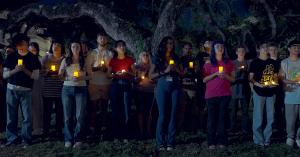 Students gathered for a candlelight vigil standing under a large Southern Live Oak tree from The Ringling Ghost documentary.