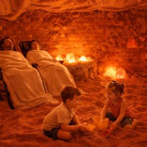 Children playing in Himalayan salt while parents relax during a halotherapy session inside a salt therapy room designed for family wellness.