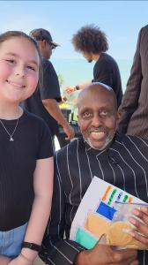 Charlie LeRoy and Bill Duke smiling as Charlie gives him a birthday gift.