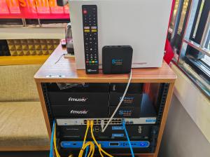 A physical demonstration rack of the FMUSER hotel IPTV system, showing the FBE013 set-top box, FBE 015 PLUS remote, network switch, Tuner to IP Gateway, and Multi-Channel CI-Receiver