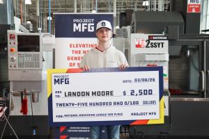 A student standing in a machining lab holding a large check made out to him for $2,500 and says National Machining League 3rd Place