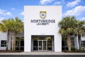 A photo showing the front facade of Northbridge University's Orlando, Fla., campus, a white building with double doors and palm trees on each side.