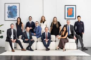 Corporate team portrait of professionals in business attire seated and standing together in a modern office setting, representing authentic human-led corporate headshots for brand trust.