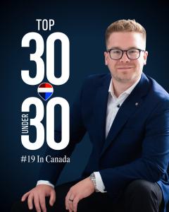Chris Hendriks, a Realtor wearing a blue blazer and glasses, posing for his Top 30 Under 30 award recognition.