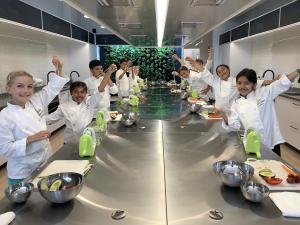 Students cooking in chef coats in Little Kitchen Academy