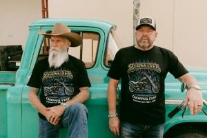 Two men from 2LaneLife standing with a mint green antique truck behind them.