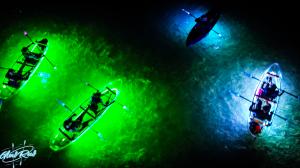 Overhead photo of multiple glowing kayaks with paddlers on dark water, lit in vibrant green and blue LED lights, featuring the GlowRow logo in the corner.
