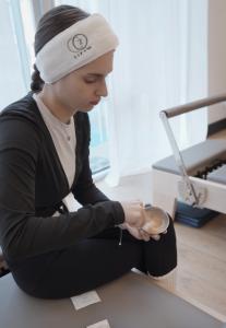 Female event guest applying skincare while in a pilates studio.