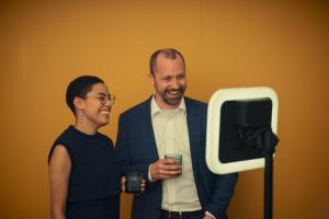 Two people giving an interview on camera, facing the video booth.