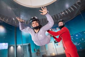 iFLY guest flying with an instructor inside the vertical wind tunnel.