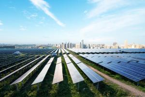 Aerial view of a solar farm with rows of photovoltaic panels generating renewable energy near an urban area.