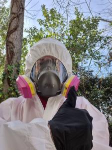 EPA AHERA-certified asbestos inspector in protective suit and respirator performing professional asbestos inspection and environmental testing.