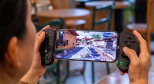 Person holding a smartphone with the Serafim S3 mobile gaming controller while playing a first-person shooter game, showing console-like controls for mobile gaming.