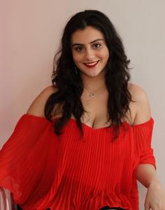 Tamara Mechael smiling in a red off-shoulder dress during a portrait photoshoot.