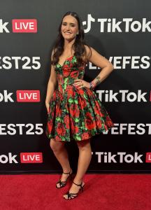 Sarah Soda on the red carpet at TikTok LiveFest 2025 wearing a red rose-print dress