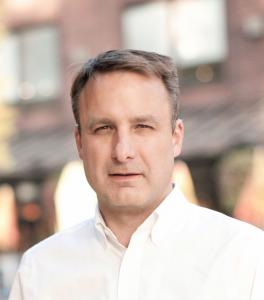 Headshot of a white man with short hair and an athletic, energetic appearance.