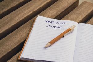 photo of a open notebook with a pen and the words on one of the sheets of paper that says "gratitude"